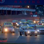 Start eines Rennens im Belcar Skylimit Sprint Cup bei Dämmerung: Mehrere Tourenwagen fahren dicht gedrängt durch die Boxengasse, Scheinwerfer leuchten, im Vordergrund ein BMW mit Startnummer 425. Im Hintergrund sind Boxengebäude und Zuschauerbereiche erkennbar, Rennatmosphäre mit hoher Dynamik.